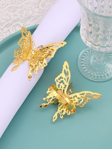 Detailed close-up of hollow butterfly napkin ring in gold on a white fabric napkin
