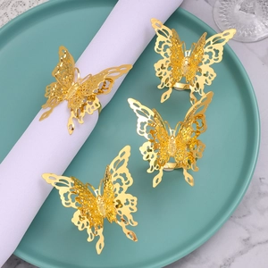 Golden hollow butterfly napkin rings on white fabric with blue ceramic plate setting