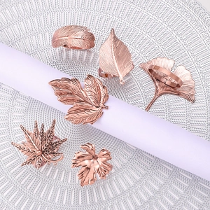 Rose gold leaf napkin rings in various botanical styles on white woven mats