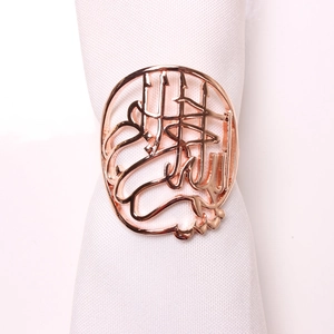 Détail du rond de serviette en or rose avec calligraphie arabe et structure évidée