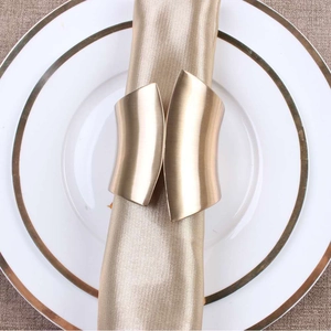 Portatovagliolo dorato in metallo a forma di ala su elegante tessuto di raso champagne