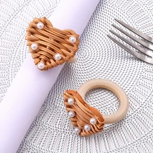 Handmade woven heart napkin ring with pearls and wooden base on a white napkin