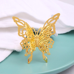 Elegant gold hollow butterfly napkin ring with double-layer design on a ceramic plate