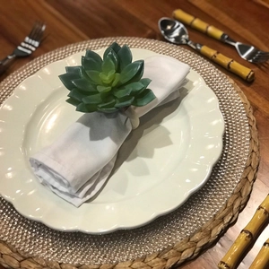 Detail of creative succulent napkin ring with green artificial plant on white napkin