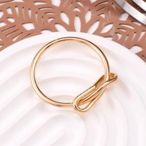 Elegant gold metal bow napkin ring with polished knot design on a decorative tray