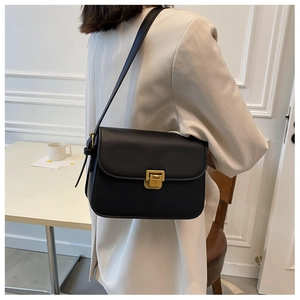 Detail of a black leather crossbody bag featuring a matte gold buckle and clean edges