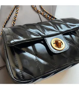Détail d'un sac bandoulière noir en cuir PU matelassé avec fermoir tournant doré brillant