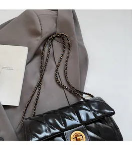 Détail du sac bandoulière en cuir matelassé noir avec chaîne dorée et fermoir pivotant