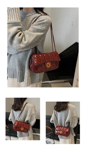 Détail d'un sac bandoulière matelassé rouge bordeaux en similicuir avec boucle dorée et chaîne