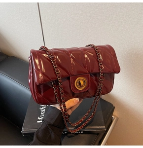 Détail du sac à bandoulière matelassé bordeaux avec fermoir doré et bandoulière chaîne