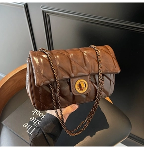 Détail du sac matelassé marron foncé avec fermoir rotatif doré et bandoulière en chaîne