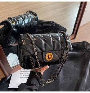 Détail du sac bandoulière en cuir matelassé noir avec fermoir tournant doré et chaîne