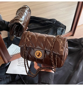 Détail d'un sac bandoulière matelassé marron foncé avec fermoir doré et bandoulière chaîne