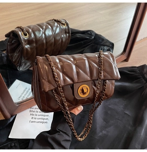 Détail du sac matelassé en cuir ciré marron foncé avec fermoir rotatif doré et chaîne