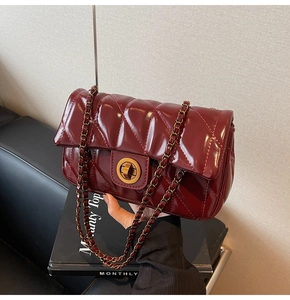 Détail du sac bandoulière matelassé bordeaux avec chaîne dorée et fermoir rotatif