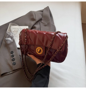 Vue détaillée d'un sac matelassé bordeaux avec un fermoir rotatif en métal doré