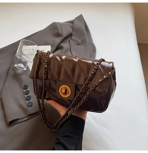 Détail du sac matelassé en cuir ciré marron foncé avec fermoir doré et bandoulière