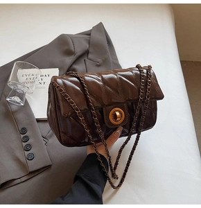 Détail du sac matelassé en cuir huilé marron foncé avec fermoir doré et bandoulière chaîne