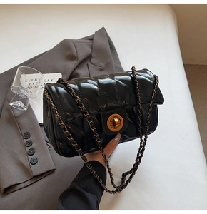 Détail du sac sous l'aisselle en cuir matelassé noir avec chaîne dorée et fermoir