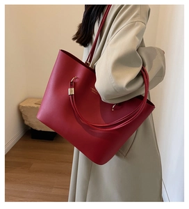 Détail du sac cabas rouge de mariée avec boucles dorées porté par un mannequin en trench