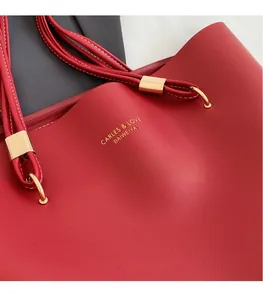 Gros plan d'un sac cabas en cuir rouge avec logo doré et détails d'anneaux dorés