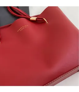 Détail d'un sac cabas en cuir rouge avec lettrage doré et boucle métallique élégante