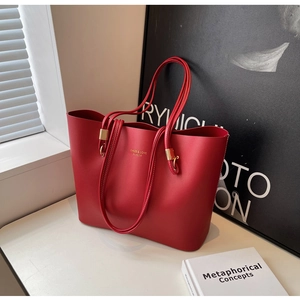Gros plan détaillé du sac cabas rouge mat avec boucles métalliques dorées et lettrage embossé