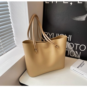 Détail du sac cabas beige clair avec fines bandoulières et boucles dorées en métal