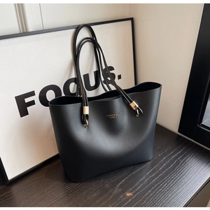 Détails d'un grand sac cabas noir en cuir PU avec logo doré et finitions métalliques chic