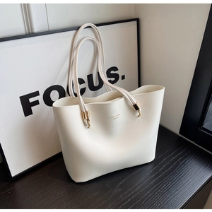 Détail du sac cabas en cuir crème avec logo doré et doubles poignées élégantes