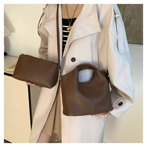 Close-up of brown lychee grain leather handbag set with silver hardware and ring handle