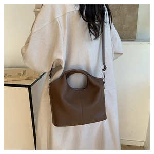 Detail of dark brown lychee grain leather handbag featuring hollow semi-circle handles