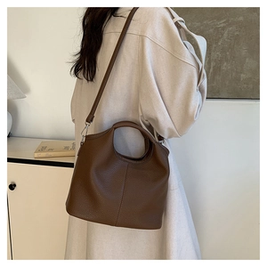 Model wearing dark brown lychee texture tote bag with crossbody strap and handle