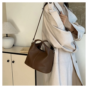Detail of dark brown leather bucket bag showing reinforced stitching and circular handle