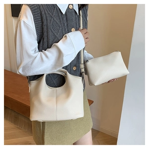Detail of cream white bucket bag set showing pebble leather texture and crossbody strap