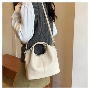 Close-up of creamy white lychee grain leather handbag with adjustable strap and stitching