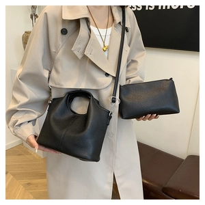 Detail of black pebbled leather bucket bag with matching pouch on a beige trench coat