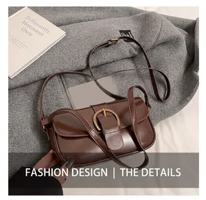 Detail of vintage brown glossy leather crossbody bag with round metal buckle on coat