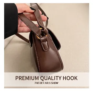 Detail of dark brown leather bag with golden D-ring hook and neat stitching