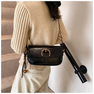 Model view of a black faux leather shoulder bag with a gold buckle and elegant styling