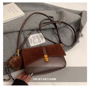 Detalle del bolso bandolera retro de cuero marrón con hebilla dorada y panel de ante
