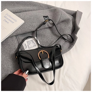 Detail of glossy black leather handbag with a prominent golden horseshoe metal buckle