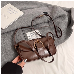 Detail of dark brown retro shoulder bag with a gold ring buckle on grey wool coat