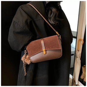 Detail of brown faux suede and matte leather crossbody bag with golden square twist lock