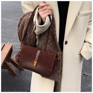 Brown patchwork handbag featuring suede textures and a gold metal clasp in an autumn setting