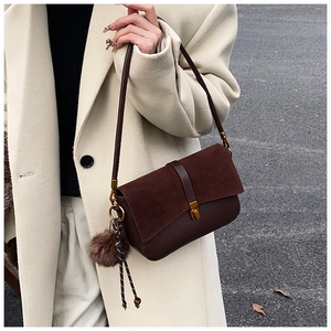 Detail of suede and leather mix crossbody bag with gold buckle and plush charm