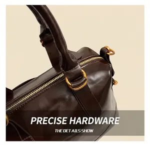 Dettaglio della borsa in pelle lucida marrone con anello in metallo dorato e zip