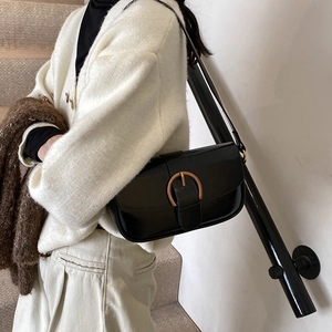 Schwarze Retro-Leder-Achseltasche mit goldener Hufeisenschnalle, von Model stilvoll getragen