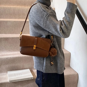 Brown frosted leather crossbody bag with tassel detail and gold buckle shown on model