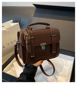 Close-up of vintage brown leather satchel with metal push-lock and handle on silk lining